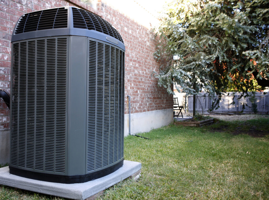 High efficiency modern heat pump unit on a slab next to a brick house in DC.