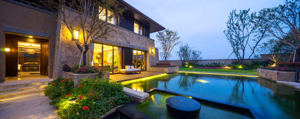 The exterior of a large modern home lit up with outdoor lighting at dusk.