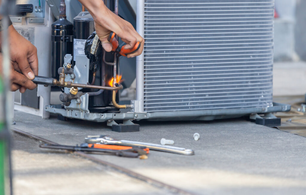 Close view of technician's hands performing maintenance on a heat pump.