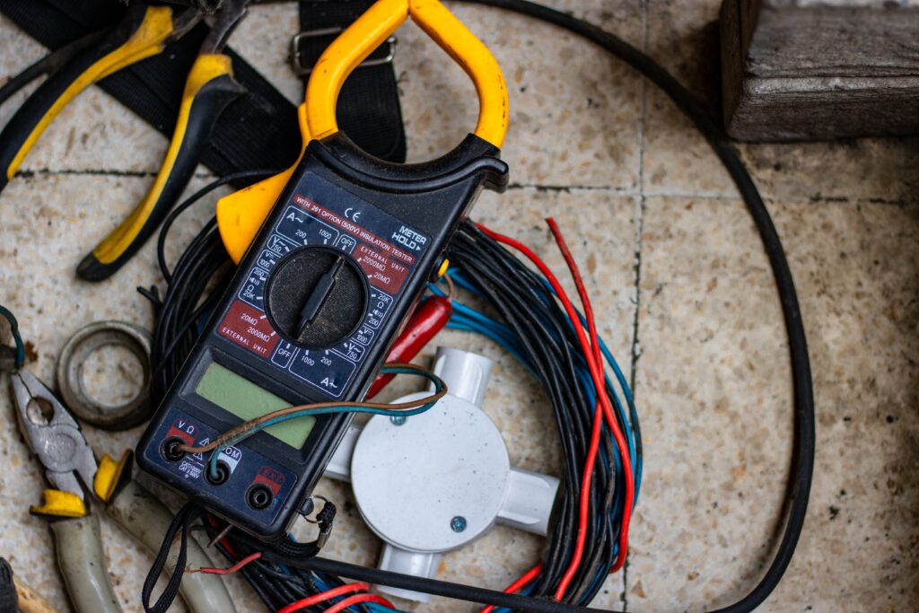 Various electrician tools lying on a tile floor.