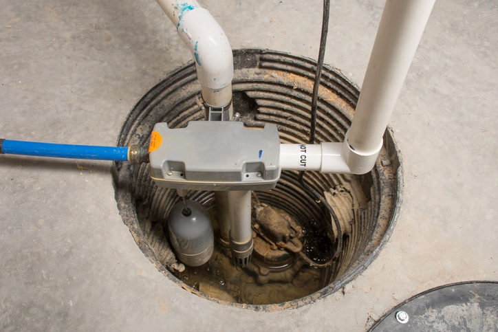 A sump pump installed in a basement of a home with a water-powered backup system.