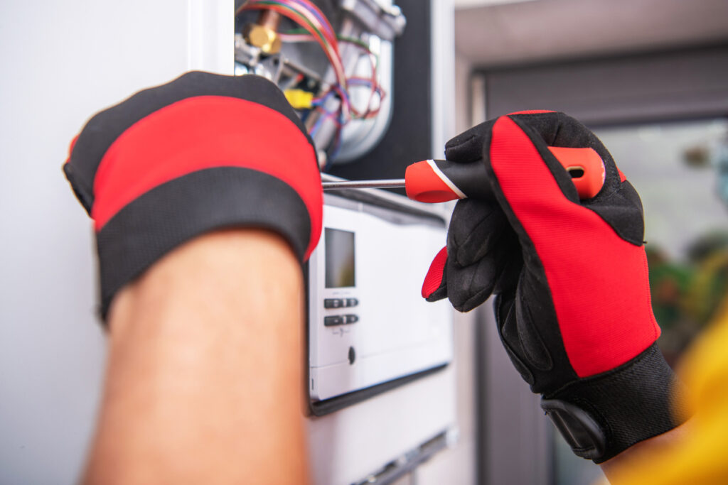 Close view of HVAC technician's gloved hands repairing a heater.