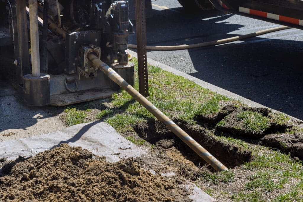 Low-angle view of trenchless laying of communications, fiber optic, and water pipes with horizontal directional drilling machine in process.