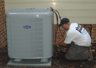 Technician installing a Carrier HVAC unit outside a home.