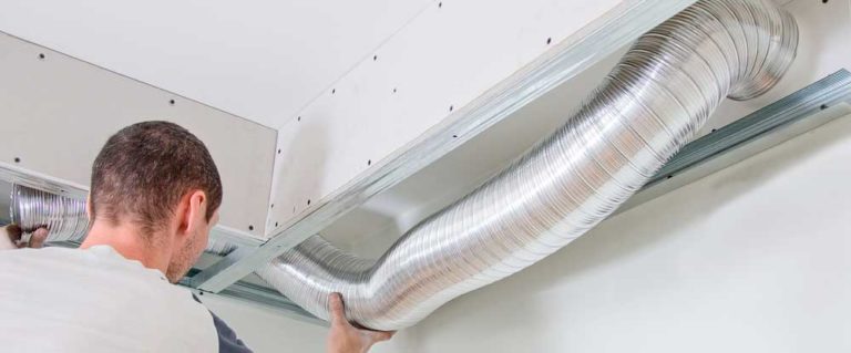 Technician installing HVAC ductwork in ceiling of a home.