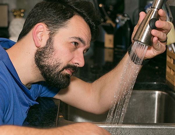 Technician repairing a kitchen sink faucet.