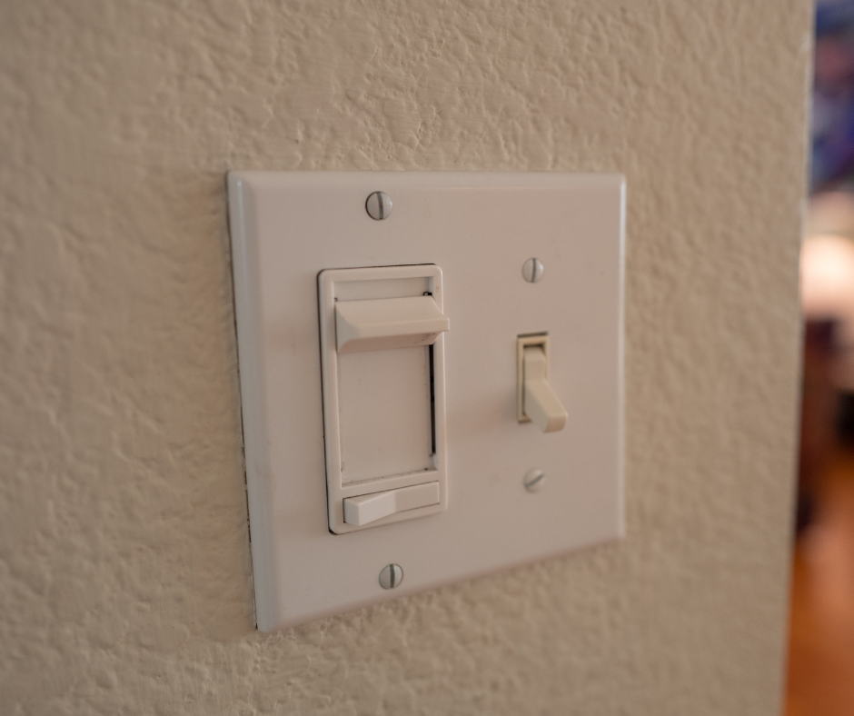 Light switch with dimmer switch on a white wall.