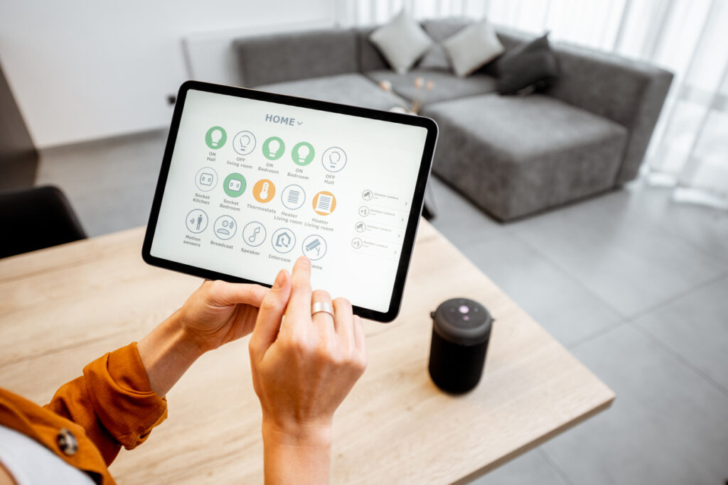 Young woman controlling home with a digital touch screen panel. Concept of a smart home and mobile application for managing smart devices at home.