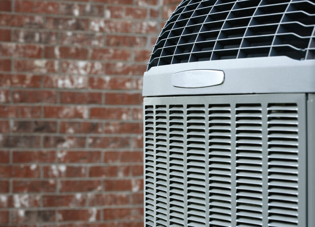 Close-up of high-efficiency modern HVAC unit installed next to a brick home.