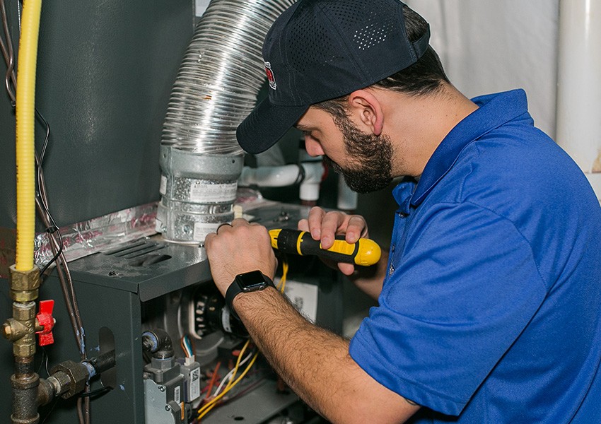 Technician repairing a furnace system in a home.