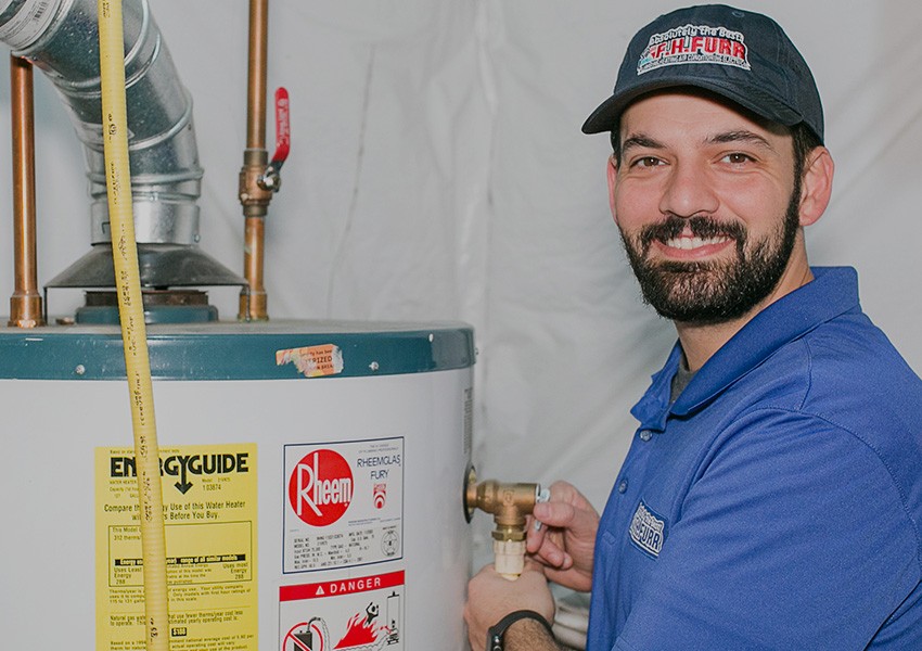 F.H. Furr team member smiling next to water heater.