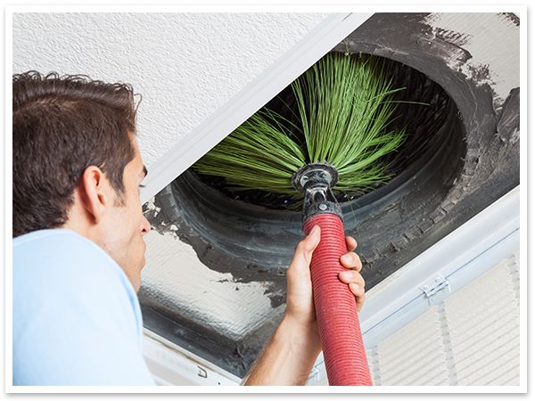Technician using a giant brush tool to clean air ducts.