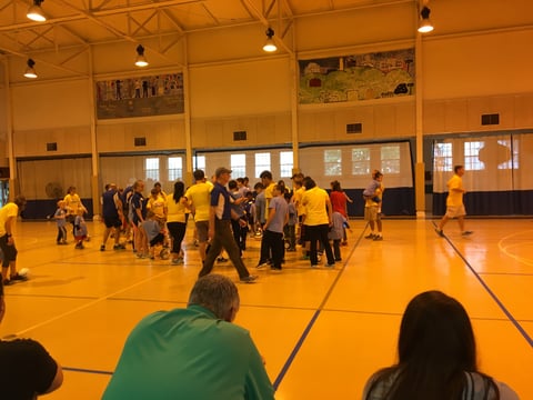 Group of kids together in a gymnasium, with parents watching from the bleachers.