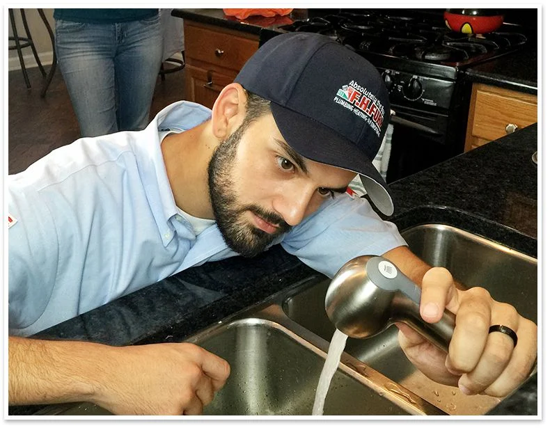 Technician fixing a kitchen sink faucet.