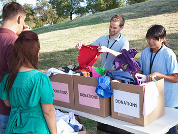 F.H. Furr staff handing out donations from carboard boxes on a table outside at a community event, with sunny field in background.