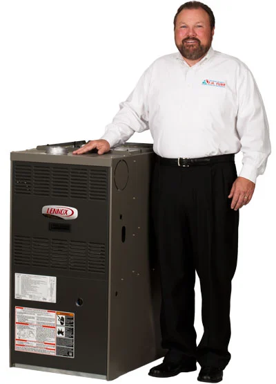 F.H. Furr standing next to a Lennox furnace with one hand on the unit while smiling.