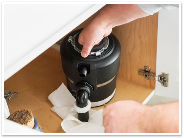 Plumber cleaning garbage disposal unit before installation 