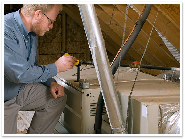 Technician completing a heating maintenance & inspection check in an attic