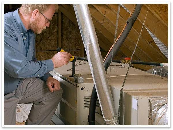 Technician testing HVAC system in an attic.