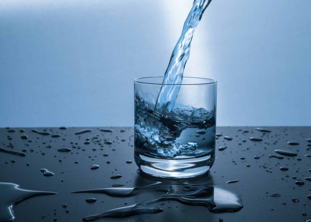 Water pouring into a glass cup on a table.