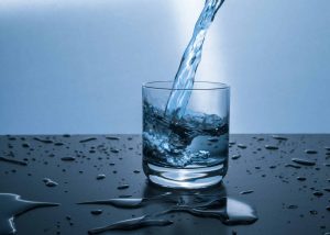 Water pouring into a glass cup on a table.