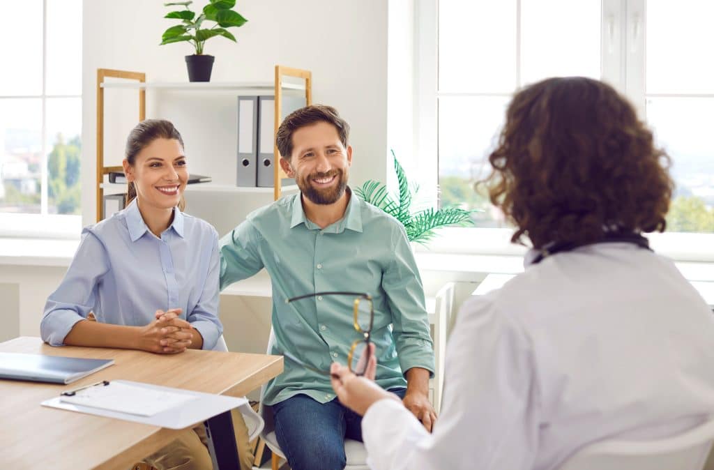 Cheerful,Family,Couple,Visiting,Doctor,Together.,Happy,Married,Man,And