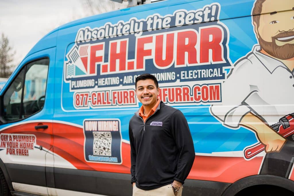 FH Furr technician smiling in front of FH Furr work van